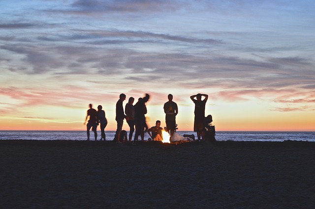 silhouettes of people on a beach at sunset, tips for traveling with a big group