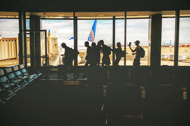 silhouettes of people boarding a plane, tips for traveling with a big group