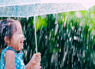 child laughing in the rain under umbrella, spring activities for kids