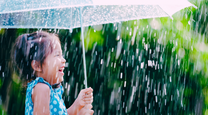 child laughing in the rain under umbrella, spring activities for kids