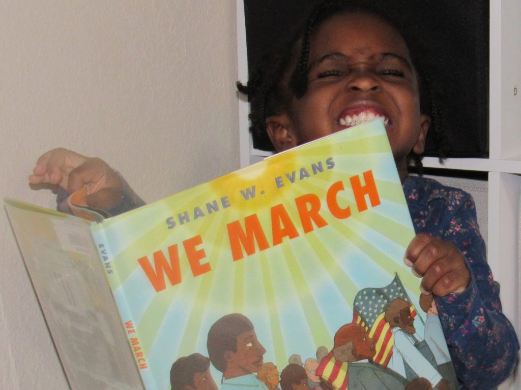 child happily reading we march, kids books about MLK