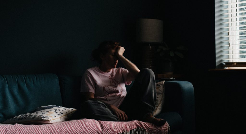 sad woman sitting on the sofa in the dark: what to say to someone who is grieving