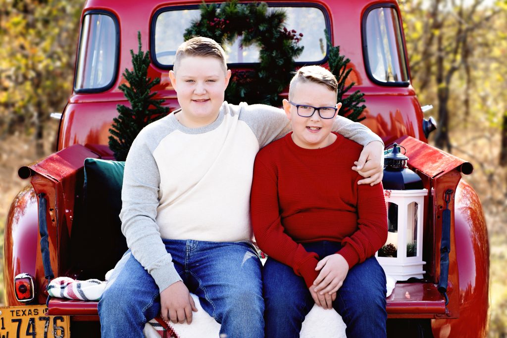 two young brothers smiling on the back of a vintage pickup truck, National Sons Day 2022