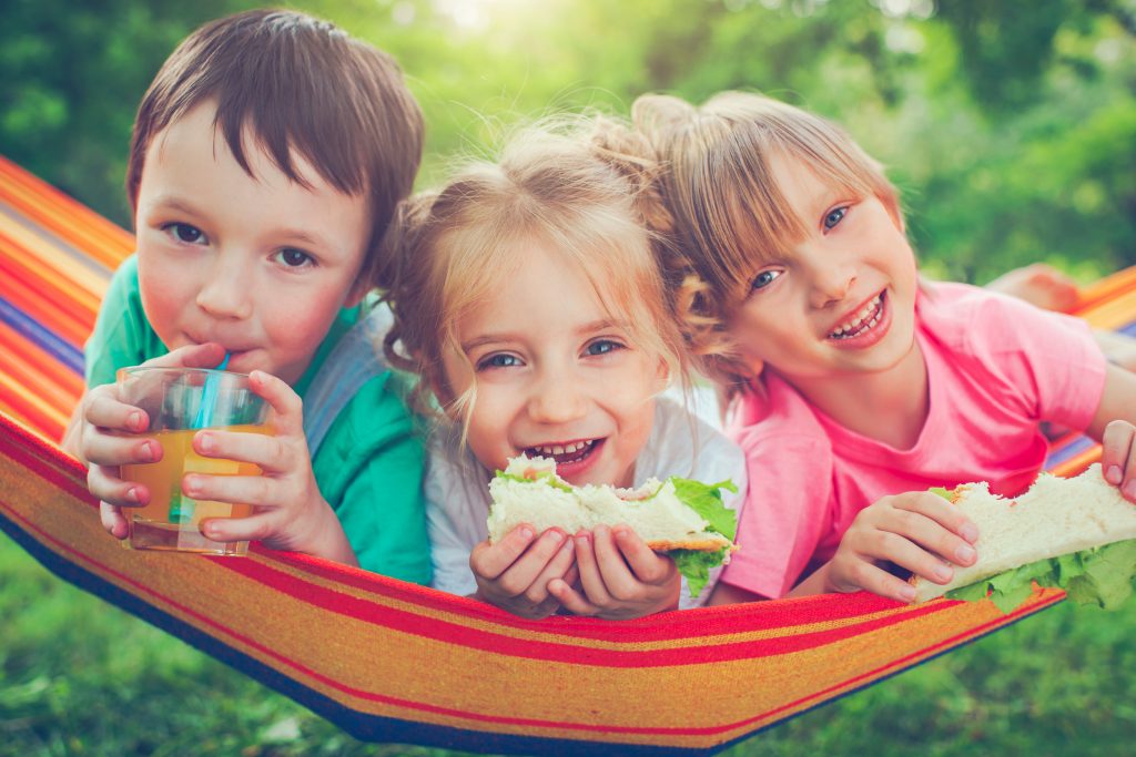 three kids eating lunch in a hammock, YMCA Dallas summer camp