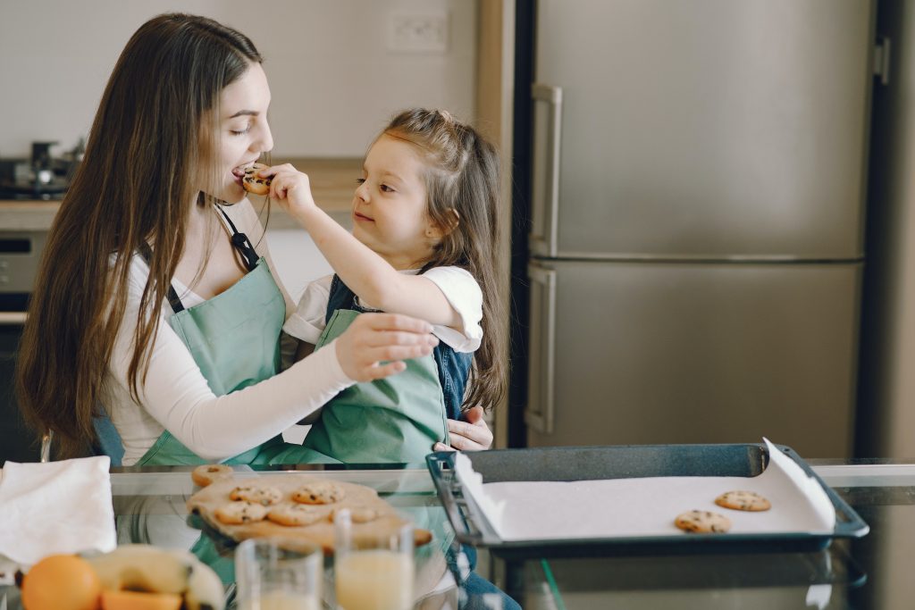 mom and young daughter tasting cookies while baking, mom with an eating disorder