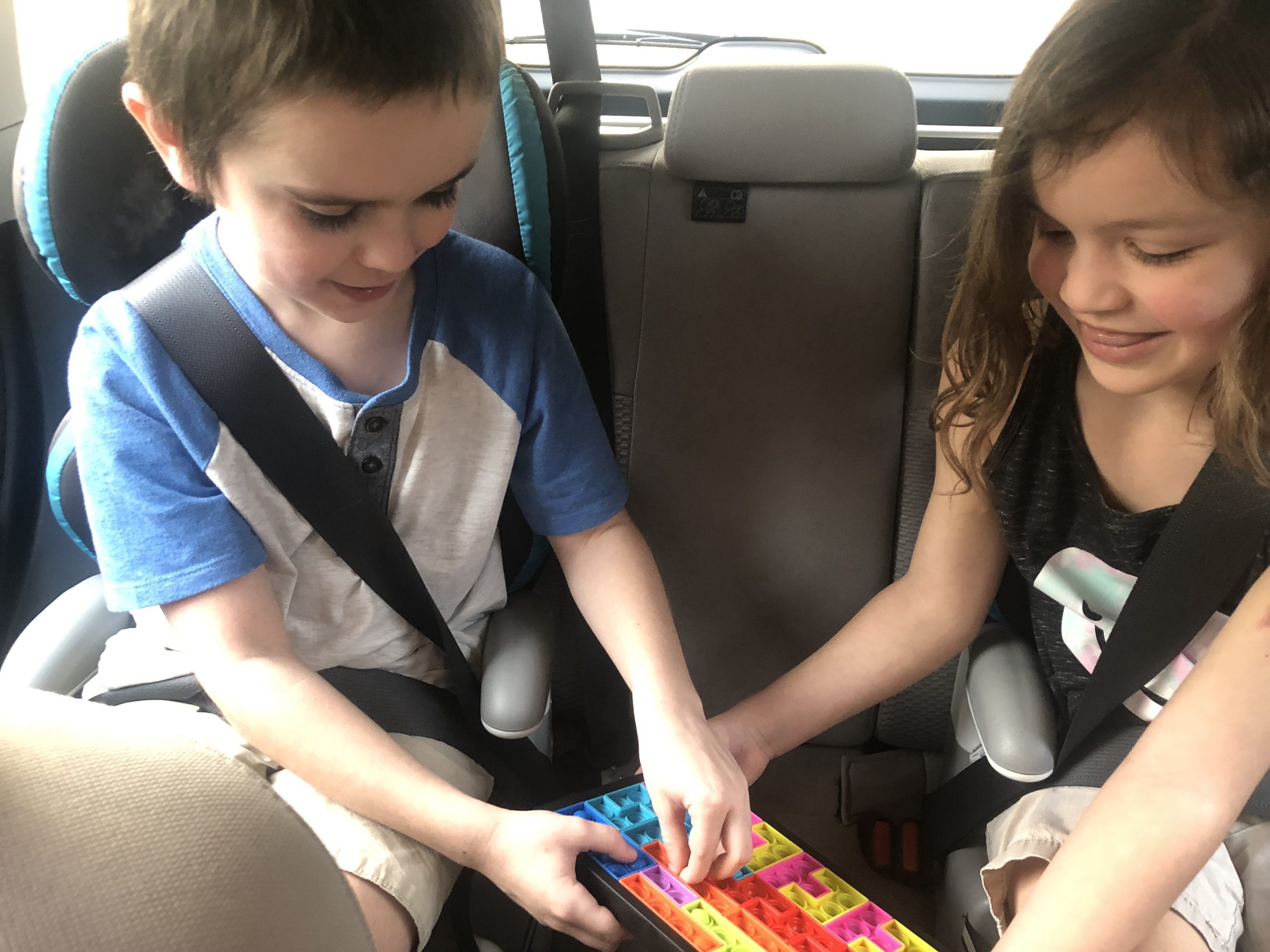 boy and girl playing with fidget toys in the car, road trip products for kids