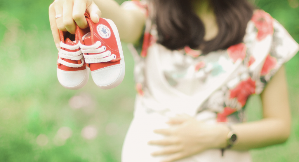 pregnant woman holing baby chuck taylors, baby products you don't need