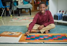 young Black student smiling while working on art project at school