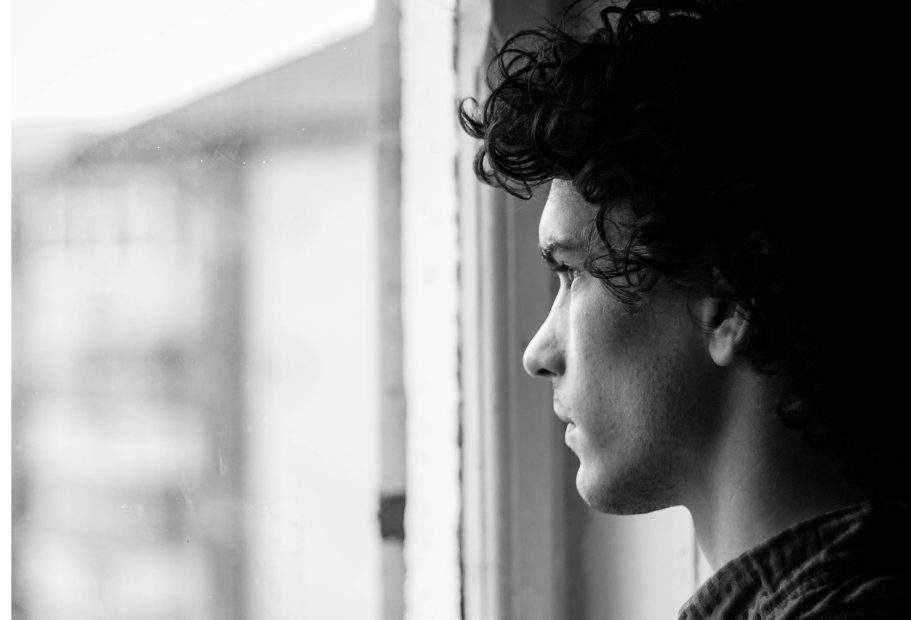 teen boy staring out window in profile, teen mental health concerns