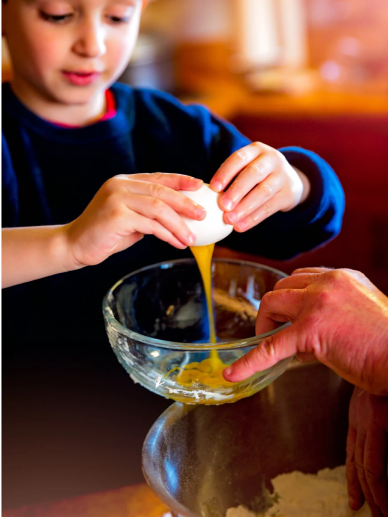 young boy cracking egg into bowl, introducing kids to other cultures