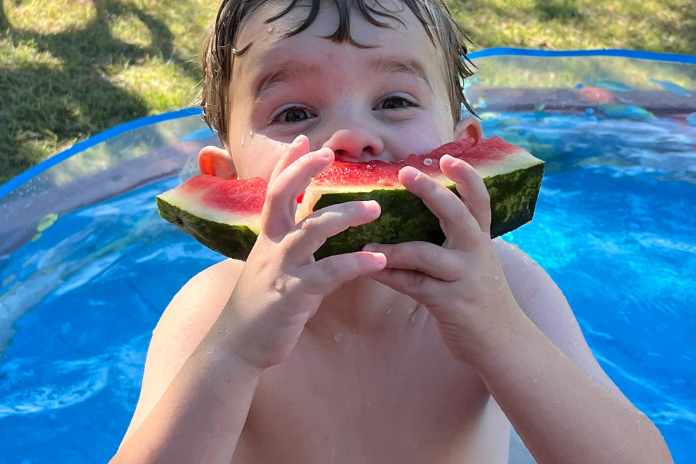 boy eating watermelon in pool