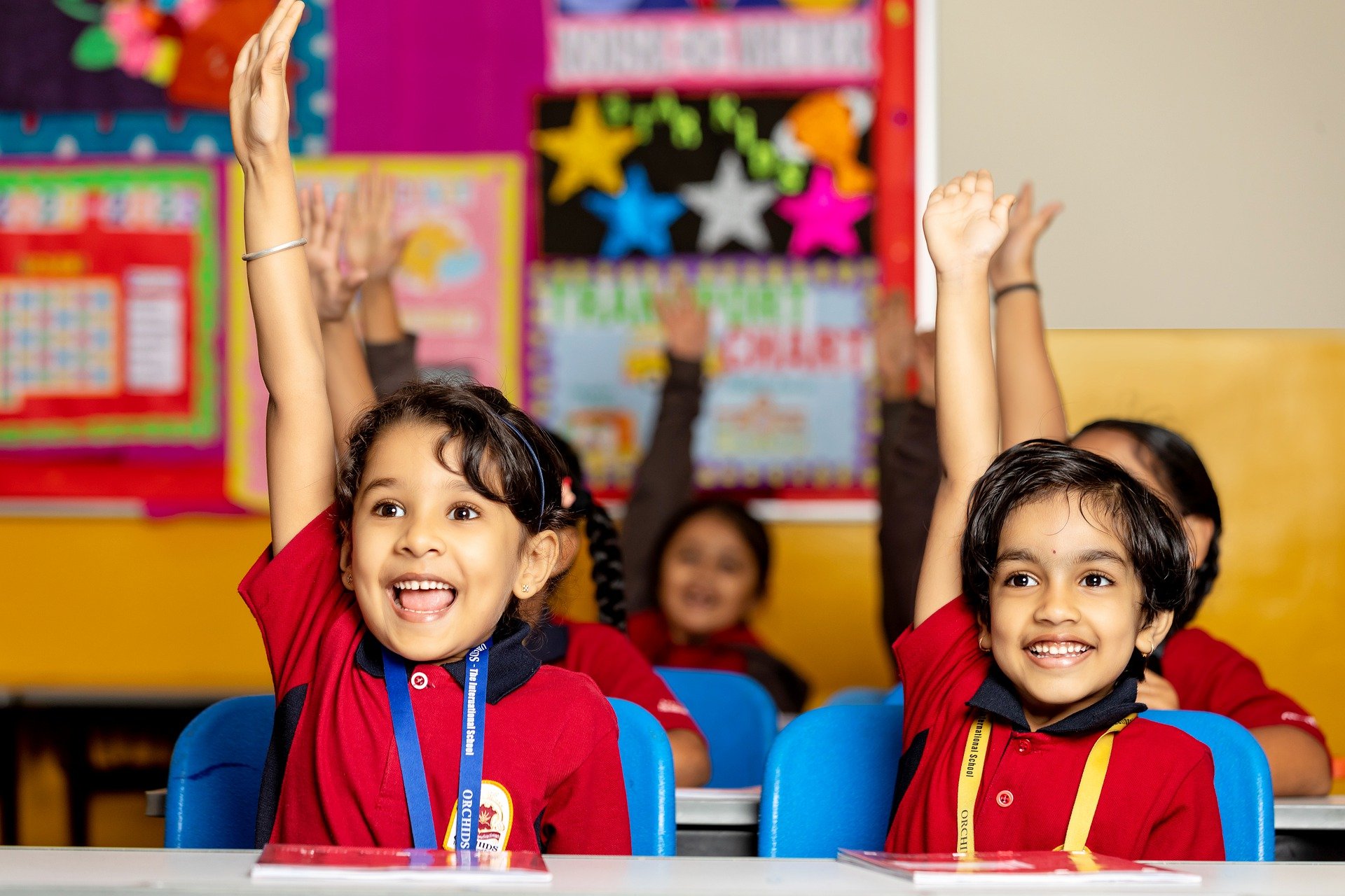 Young children raising their hands in a classroom