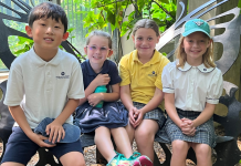 four students of Our Redeemer Lutheran School smiling while seated on a butterfly-shaped bench