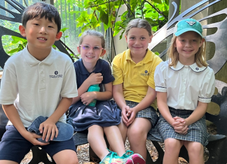 four students of Our Redeemer Lutheran School smiling while seated on a butterfly-shaped bench