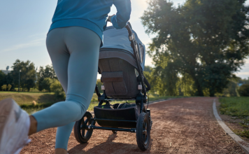 A mom pushes a baby stroller on her run outside on a running path.