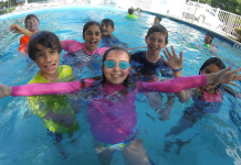 group of children smiling in a swimming pool at cooper aerobics summer day camp