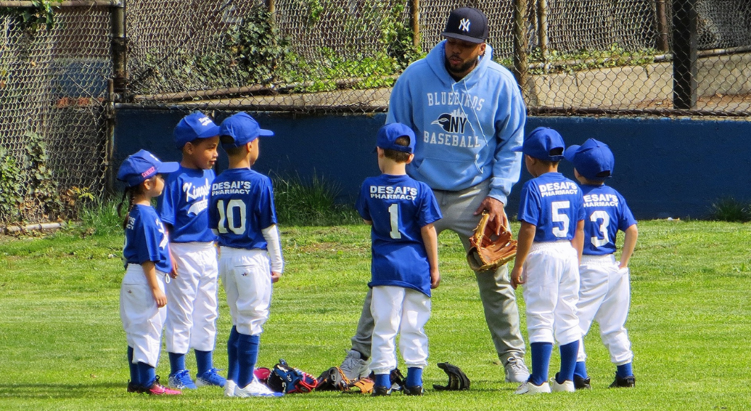 A group of young baseball players listen to their coach.