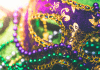 closeup of Mardi Gras mask and green and purple plastic beads