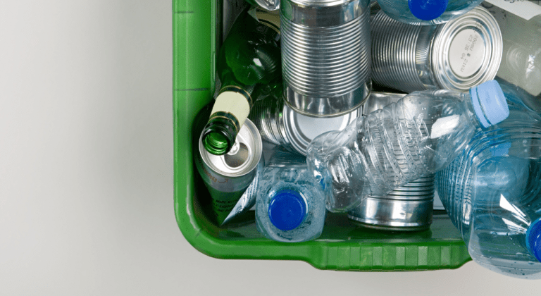 A green recycling bin with plastic bottles and tin cans.