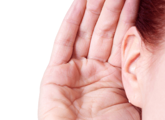 A woman holds her hand up to her ear to listen to noises.