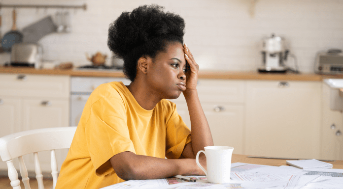 A woman looks sad as she sits at a table with cup of coffee.