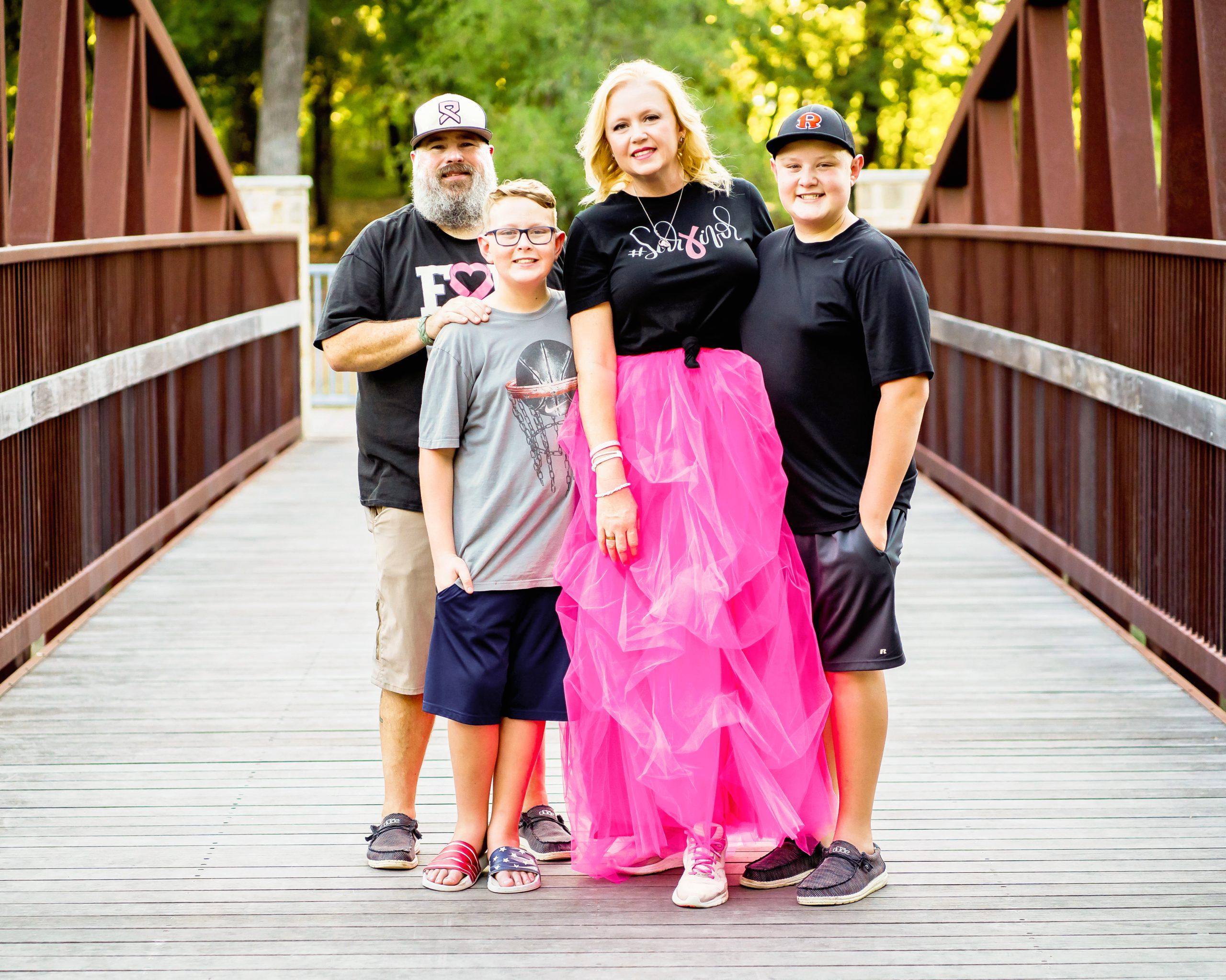 A breast cancer survivor and her family pose on a bridge.