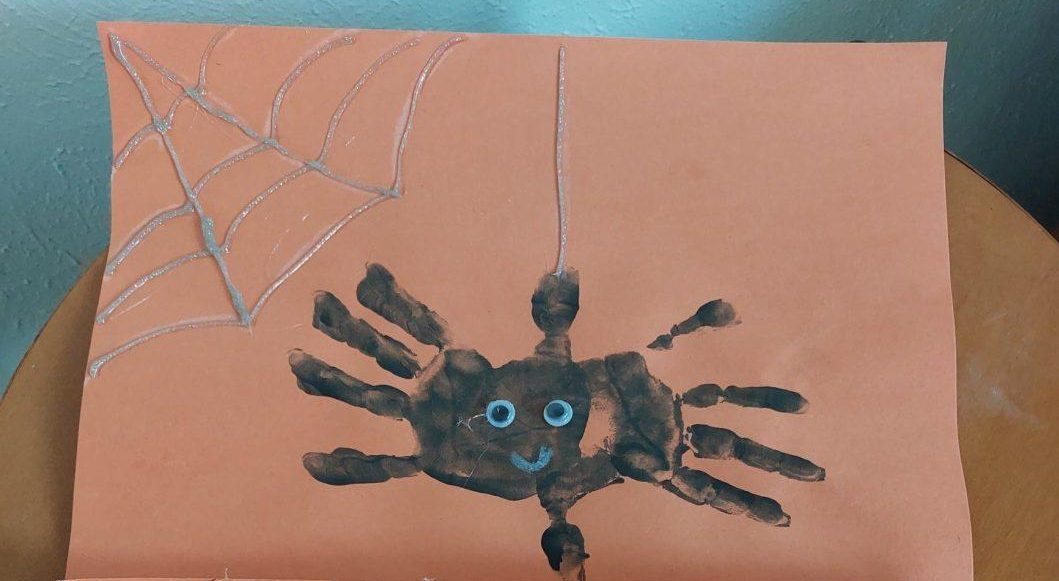 Fingerprint spiders on orange paper for Halloween craft.