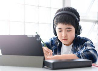 Young. boy working on a tablet with headphones on.