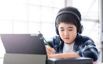 Young. boy working on a tablet with headphones on.