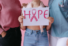 Two people stand next to a person holding a sign that says hope for breast cancer.