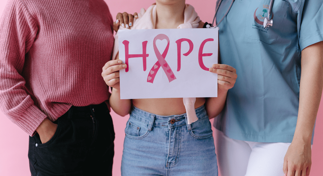 Two people stand next to a person holding a sign that says hope for breast cancer.