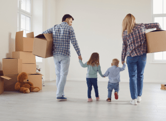 A family holds hands and moves boxes while moving.