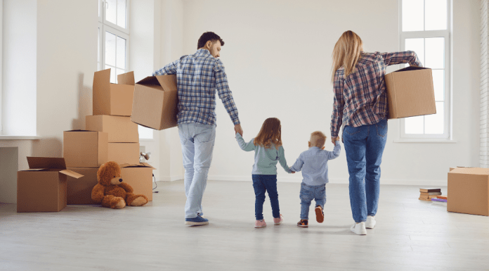 A family holds hands and moves boxes while moving.