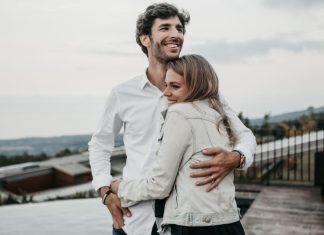 A young couple hug each other and smile.
