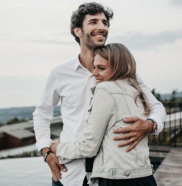 A young couple hug each other and smile.
