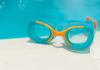 Swim goggles sitting on the side of a pool