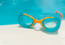 Swim goggles sitting on the side of a pool