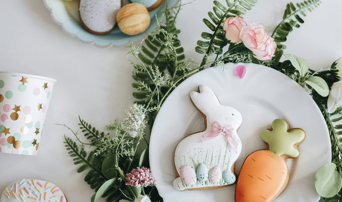 Sugar cookies shaped as an Easter bunny and carrot are served on a plate.