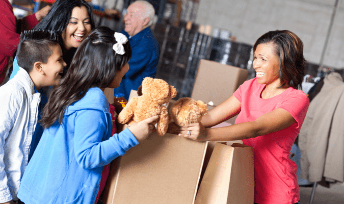 Children receive teddy bears from a volunteer.