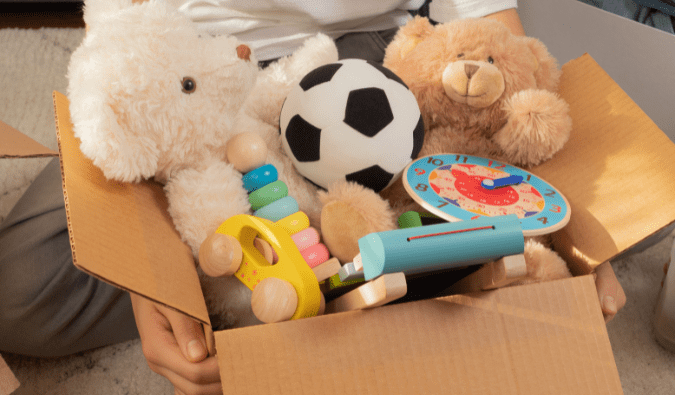 Someone carries a box of toys to donate to a charity thrift store.