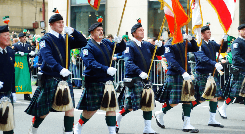 Men wearing kilts march in an Irish festival parade.
