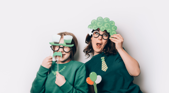 A mom and child try on silly St. Patrick's Day-themed photobooth props.