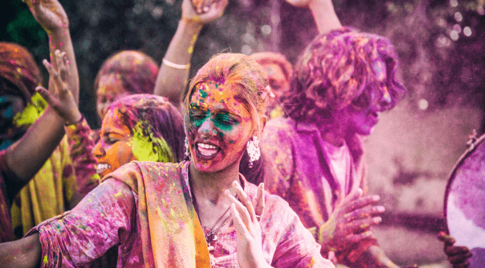 A woman covered in colored powder dances and sings at the Holi festival of colors.