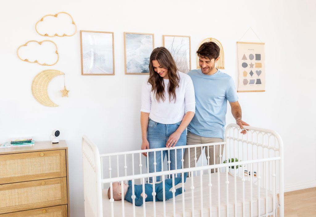 A mother and father look at their baby in his crib with a Harbor baby monitor camera