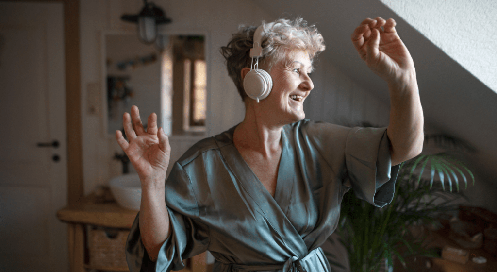 Woman dances in her silk bathrobe while listening to music in her headphones. 
