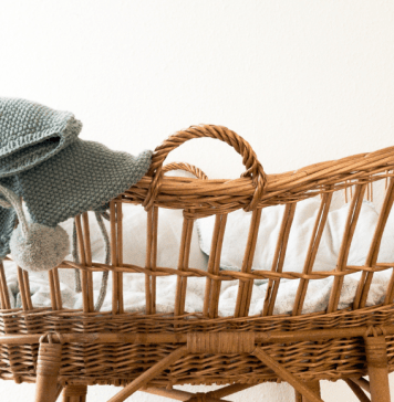 A wicker bassinet with a baby blanket draped over it