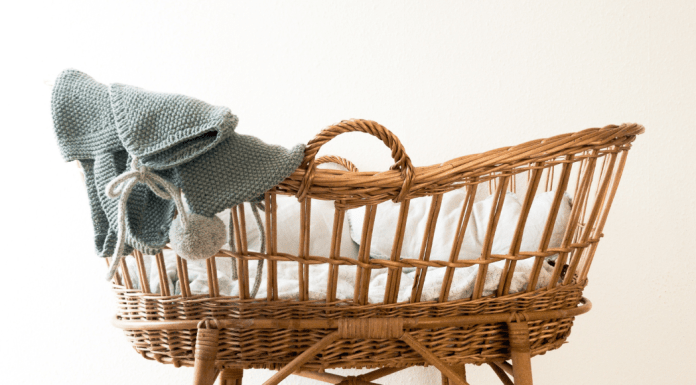 A wicker bassinet with a baby blanket draped over it